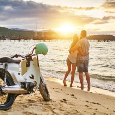 Scooter och ett par på en strand.
